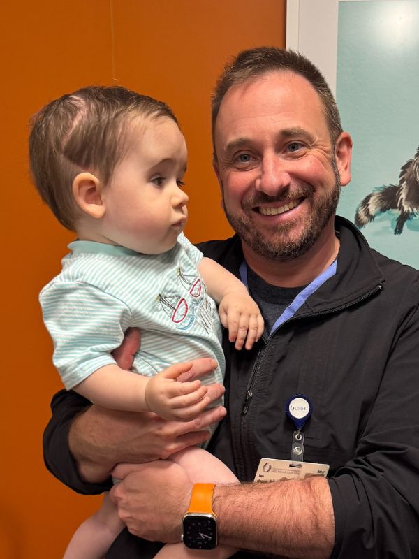 A side view of young boy after surgery for craniosynostosis, held by the doctor.